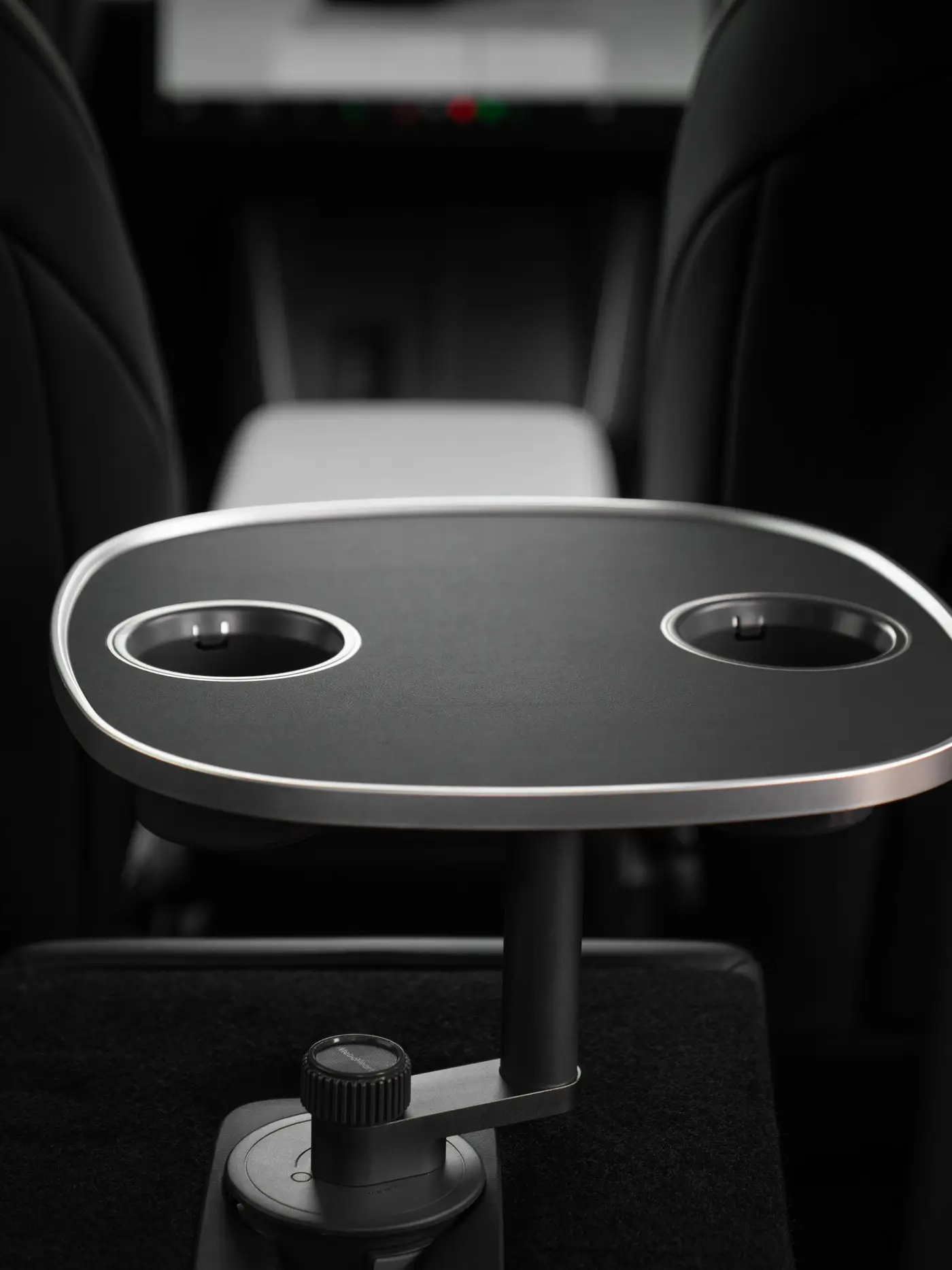 Leere schwarze Tischplatte auf dem Standfuß zwischen den Rücksitzen eines geparkten Tesla