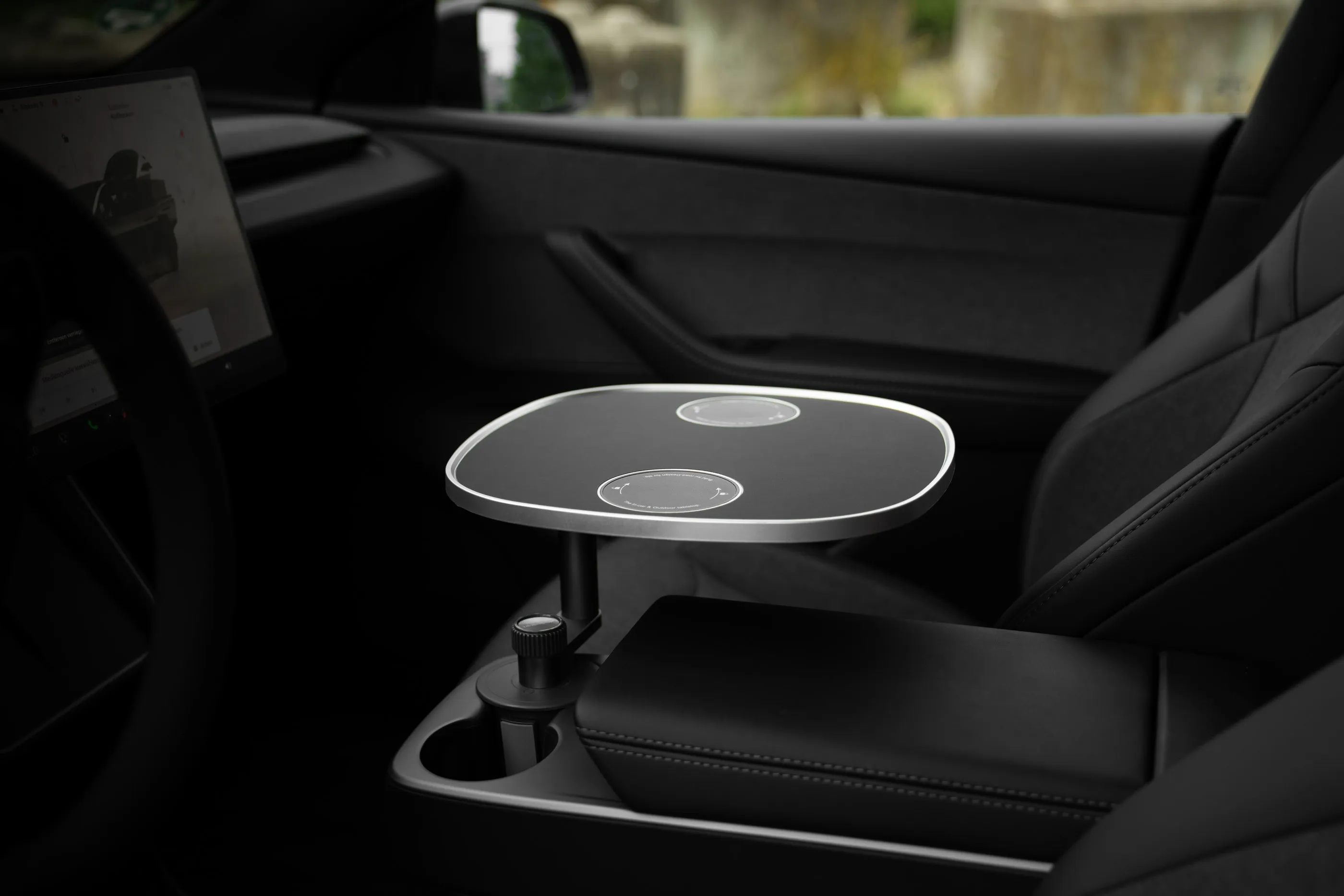 Schwarze Tischplatte auf dem Standfuß im Cupholder der Mittelkonsole, das geriffelte Klemmrad des Fußes ist sichtbar