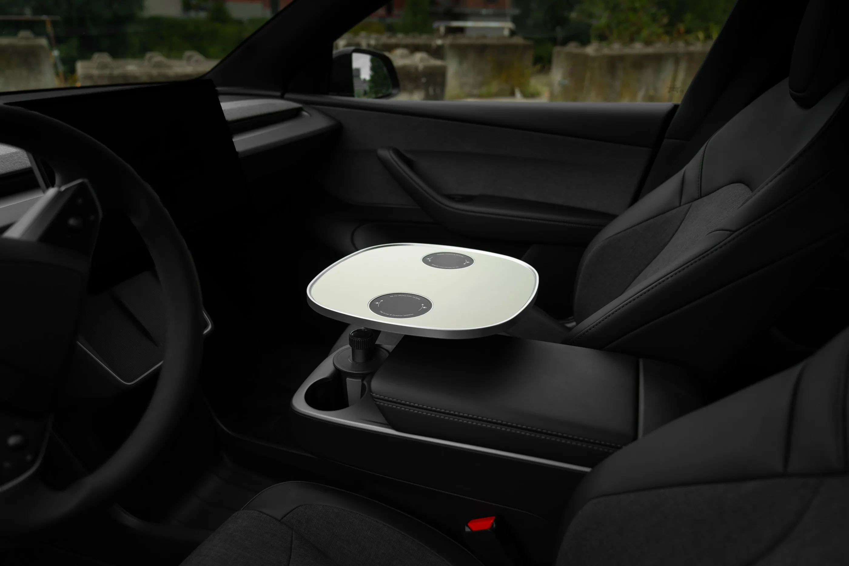 Weiße Tischplatte über der Mittelkonsole eines geparkten Tesla, Blick über das Lenkrad ins Cockpit