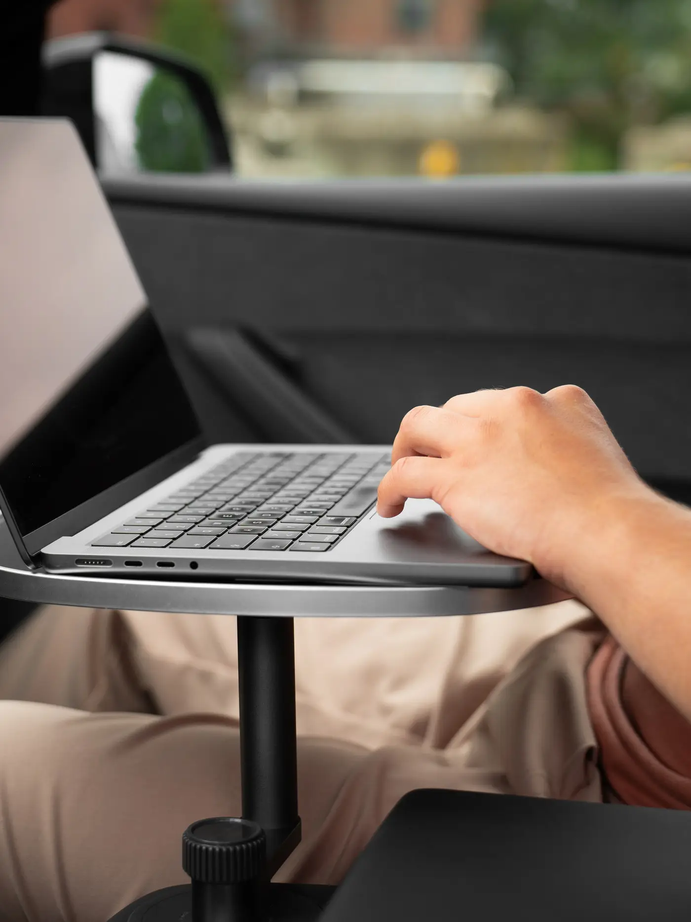 Person auf dem Beifahrersitz tippt an einem Laptop, der auf der weißen Tischplatte über der Mittelkonsole steht