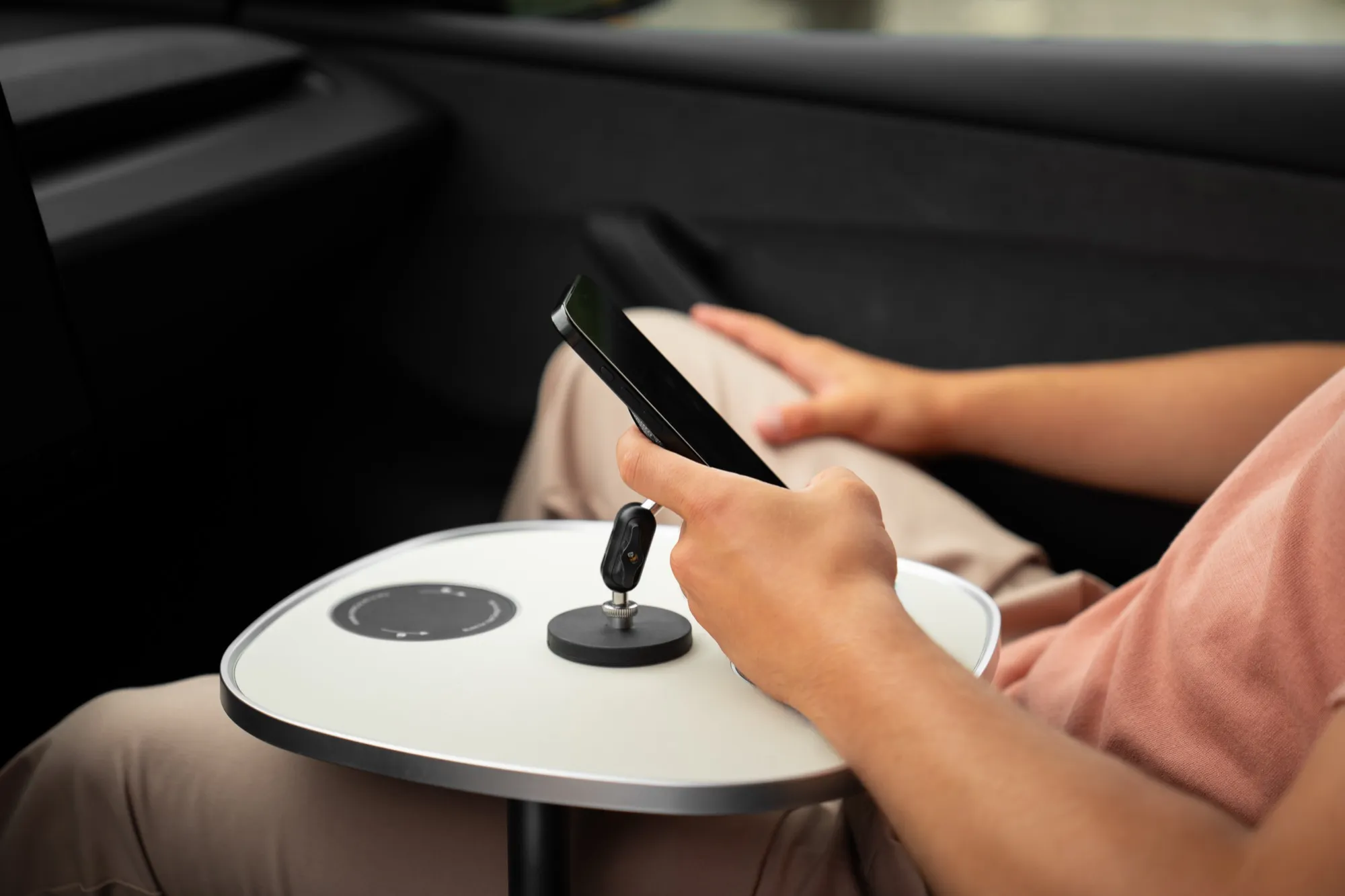 Hand nimmt ein Smartphone vom magnetischen Halter auf der weißen Tischplatte
