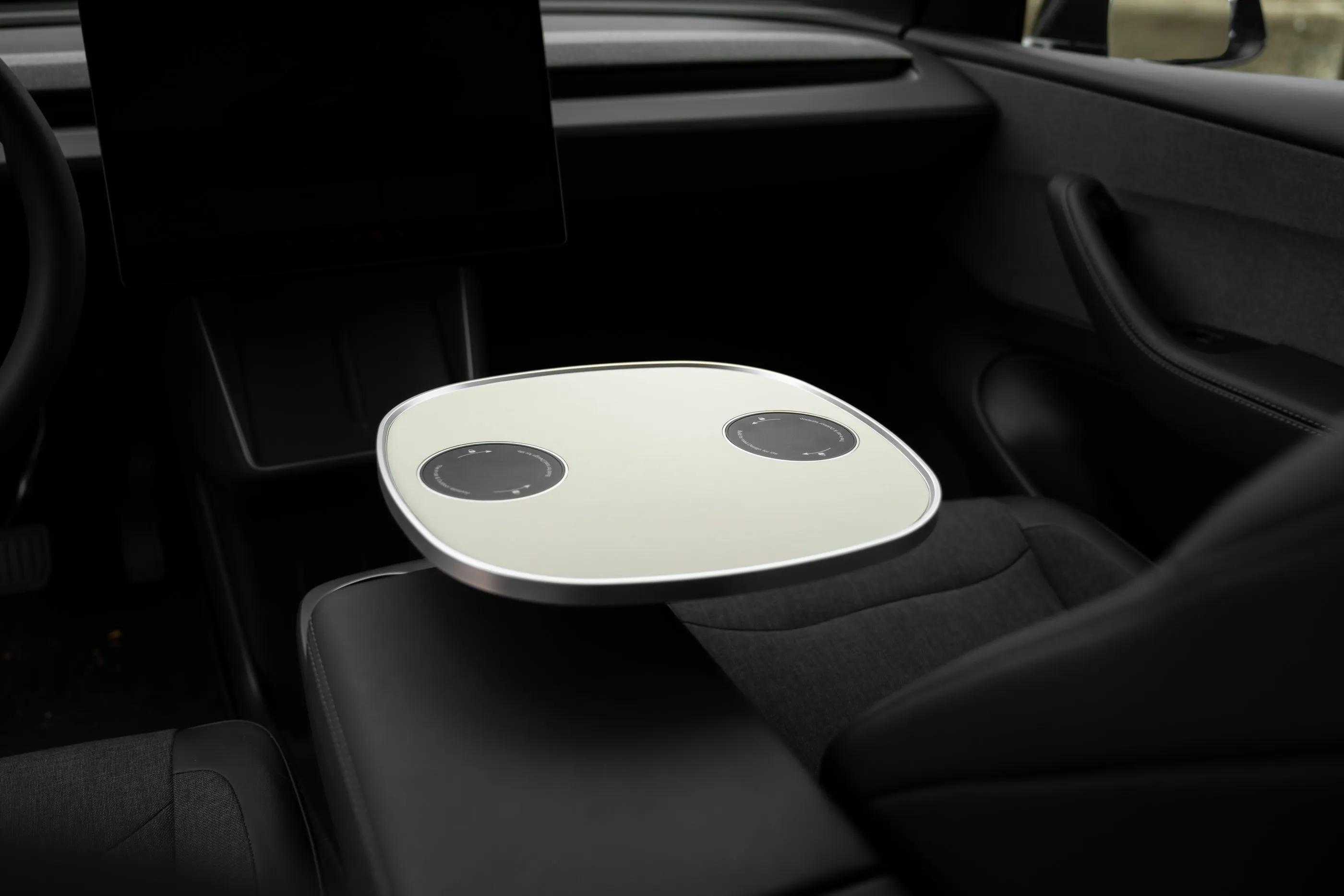 Leere weiße Tischplatte mittig zwischen den Rücksitzen eines geparkten Tesla