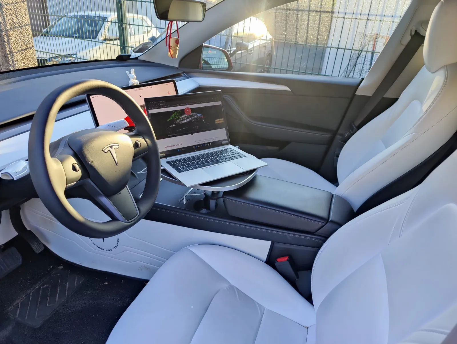 Kundenfoto: Laptop auf der Tischplatte über der Mittelkonsole eines geparkten Tesla Model Y