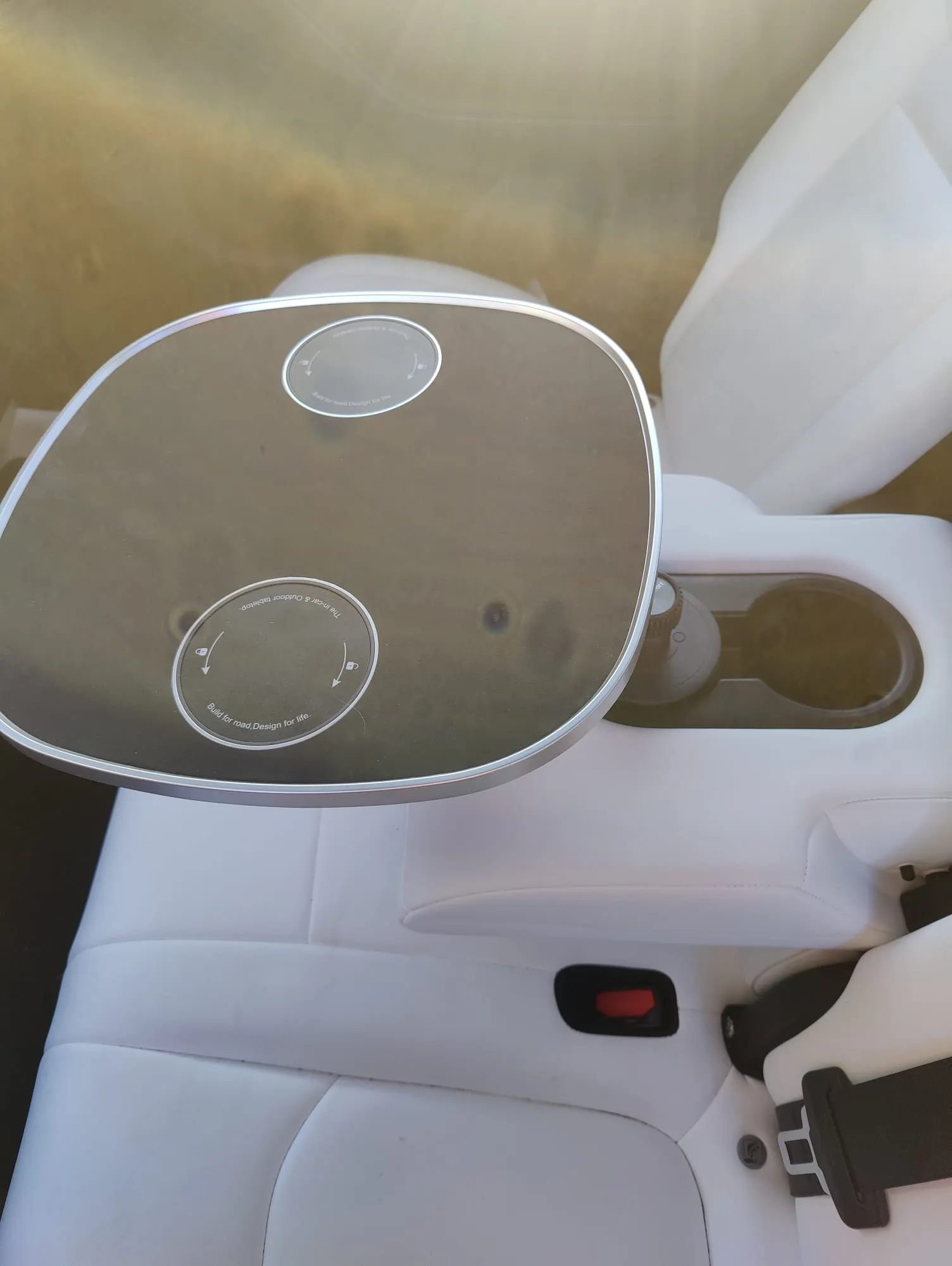 Kundenfoto: schwarze Tischplatte an der hinteren Mittelkonsole eines Tesla Model Y mit weißem Innenraum