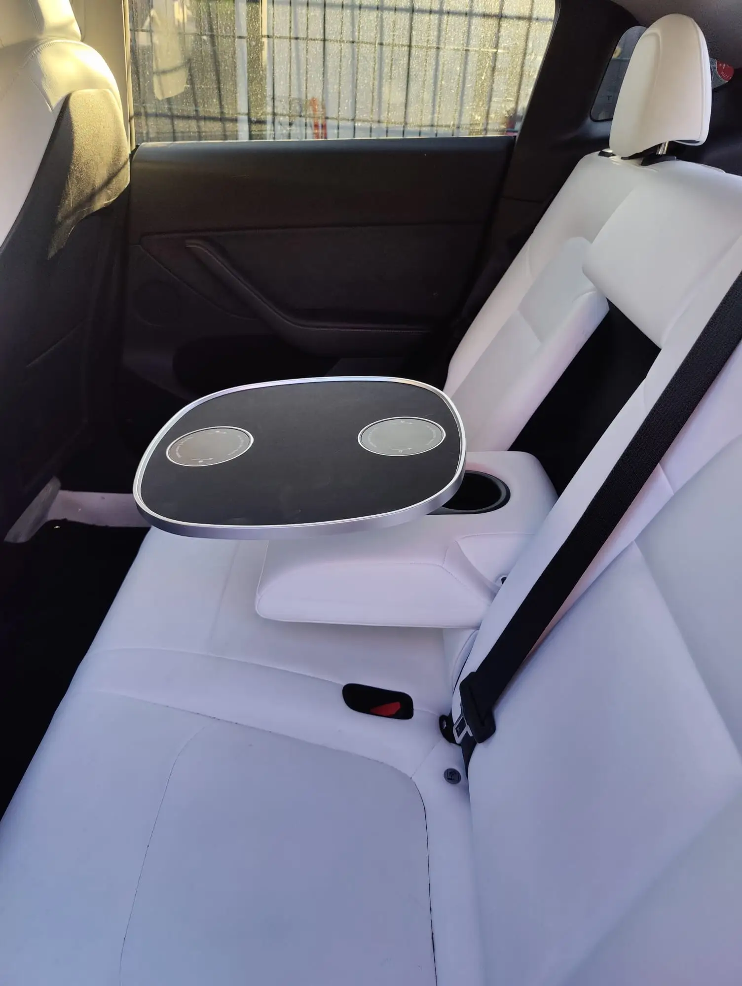 Kundenfoto: schwarze Tischplatte zwischen den Rücksitzen eines Tesla Model Y mit weißem Innenraum
