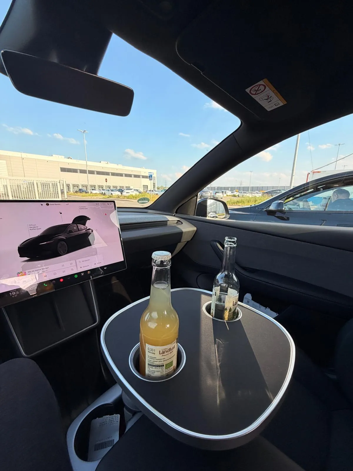 Kundenfoto: Flasche und Glas auf der schwarzen Tischplatte in einem Tesla Model Y Juniper